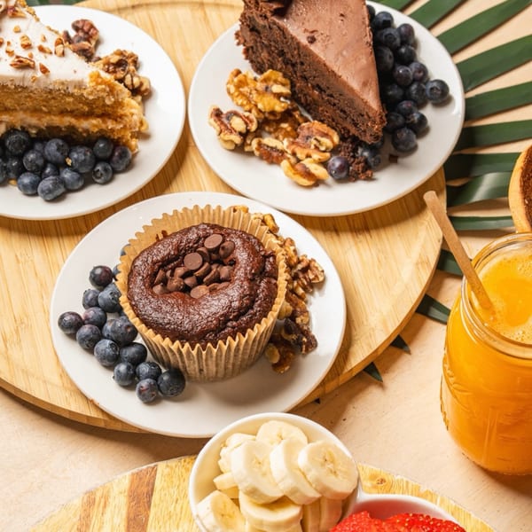 Healthy desserts: chocolate muffin, two cake slices, blueberries, walnuts, orange juice, and fruit.